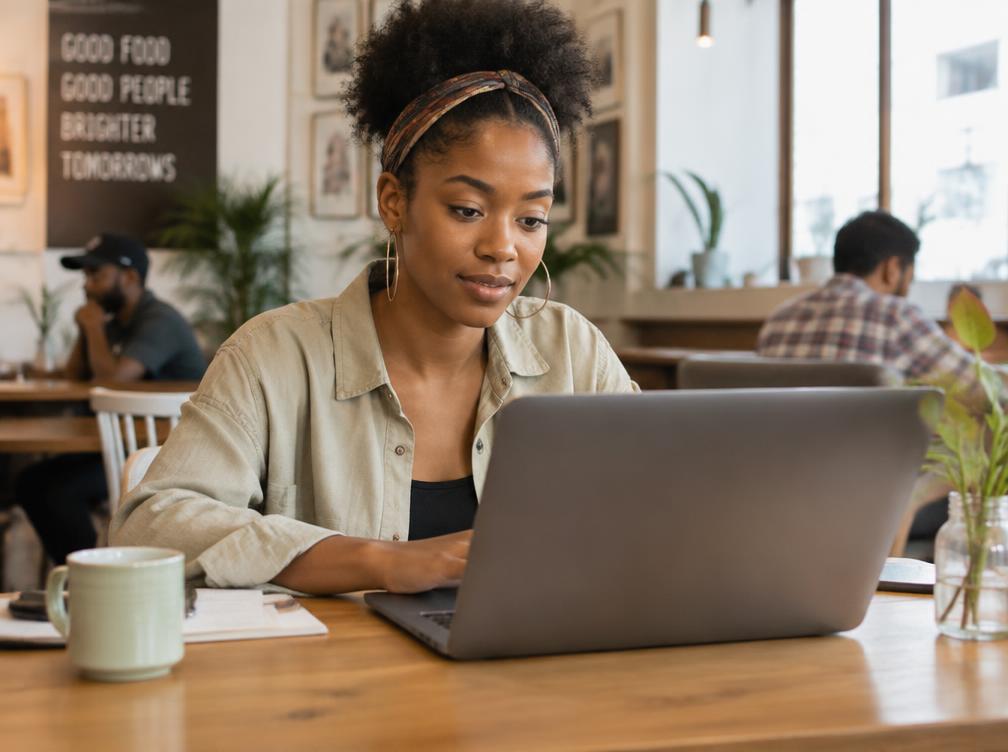 A young Black woman working on a laptop at the Thrive Career Café